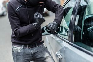 A disguised man is breaking a car window