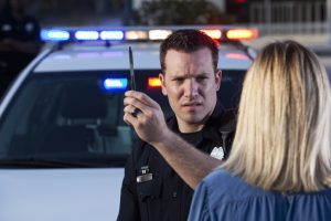 Police officer (20s) conducting sobriety test on woman.