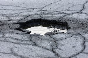 "Broken asphalt pavement resulting in a pothole, dangerous to motorists. 