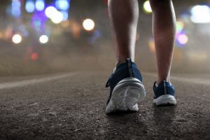 Runner feet running at night. Walking at night feet close-up.