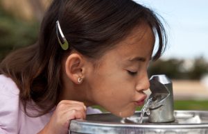 Little girl drinking from a water fountain