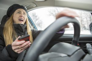 A woman holding her cell phone and screaming as she is about to cause an accident.