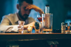 One man, sitting at the bar counter alone, he has drinking problems.