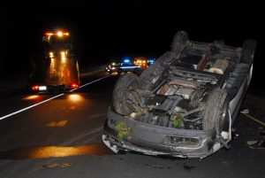 car flipped over on highway at night. rollover accident night. tow truck.